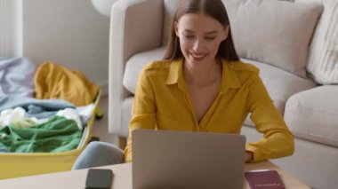 Work from everywhere. Close up portrait of young happy woman freelancer typing on laptop at hotel room, working on vacation near luggage, tracking shot, slow motion, free space