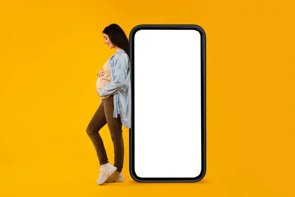 Happy Pregnant Woman Leaning Huge Blank Cellphone Hugging Her Belly — Photo