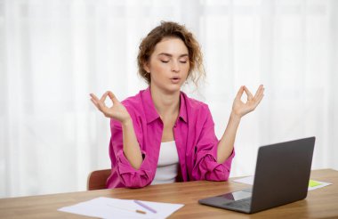 Zen Concept. Young Female Freelancer Sitting At Desk And Meditating With Eyes Closed, Calm Woman Dealing With Stress And Anxiety, Practicing Yoga While Working With Laptop At Home Office