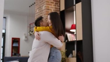 Sincere feelings. Happy young asian lady coming to her loving husband, caring middle aged man embracing and swinging her at home, tracking shot, slow motion, free space
