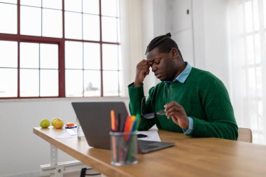 Tired Black Businessman Working Online On Laptop Taking Off Eyeglasses And Rubbing Nosebridge Having Problems With Eyesight Sitting In Modern Office. Work And Healthcare, Poor Sight Concept