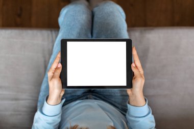 Top View Of Young Woman Using Blank Digital Tablet With White Screen At Home, Unrecognizable Female Sitting On Couch And Browsing Internet On Modern Gadget With Empty Touchscreen, Mockup