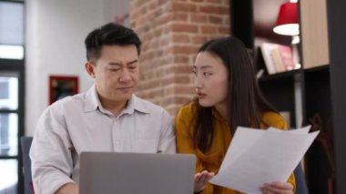 Paperwork problems. Close up portrait of emotional upset asian man and woman creating financial report at home, having troubles with data