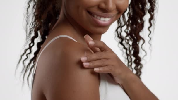 对身体的宠爱特写镜头 一个无法辨认的黑人女人在肩上擦着润肤霜 白色背景 动作缓慢 — 图库视频影像