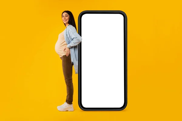 Excited Pregnant Lady Posing Huge Smartphone Blank Screen Yellow Background — Photo