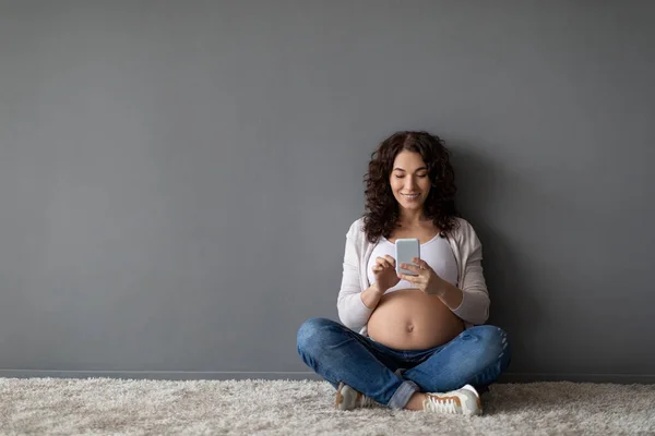 Smiling Young Pregnant Woman Browsing App Smartphone While Relaxing Floor — Foto de Stock