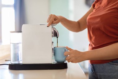 Unrecognizable Woman Turning On Coffee Machine While Preparing Morning Drink In Kitchen, Young Female Using Modern Appliance At Home, Filling Mug With Caffeine Beverage, Cropped Shot, Side View