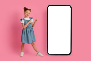 Beyaz Ekranlı Büyük Akıllı Telefon 'u işaret eden, Yeni Mobil Uygulamayı Öneren Gülümseyen Kadın Çocuk ya da Pembe Stüdyo Arkaplanının Üzerinde Dururken Web Sitesi
