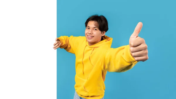 Happy Asian Teenager Guy Gesturing Kciuki Górę Pozowanie Pustym Plakatem — Zdjęcie stockowe