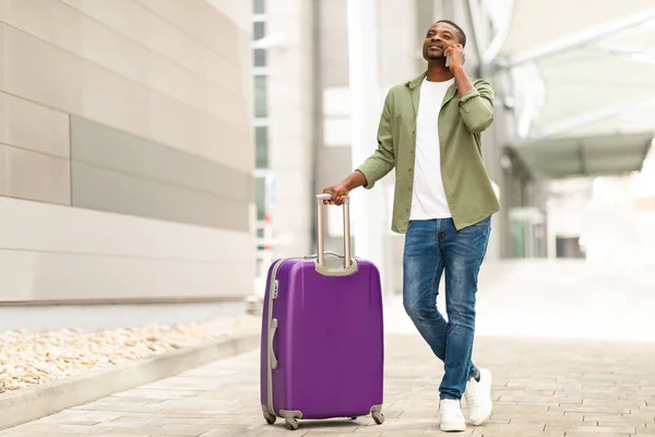 stock image Travel And Communication. Black Male Tourist Talking On Cellphone Standing With Suitcase At Modern Airport. Traveler Communicating Via Phone Going On Vacation Abroad. Always In Touch Concept