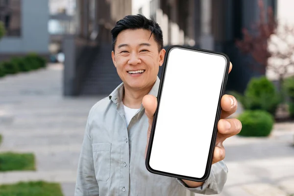 Medelålders Asiatisk Man Visar Smartphone Med Tomma Skärmen Kameran Ler — Stockfoto