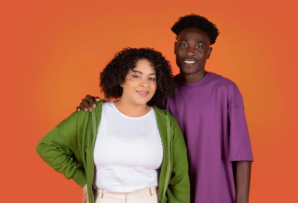 stock image Portrait of beautiful young mixed race couple, embracing, smiling at camera, happy loving millennial black guy and chubby hispanic curly woman posing on colorful studio background together