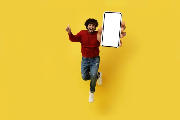 감정적으로 핸드폰을 공중으로 오르는 스크린 엄지손가락을 스마트폰을 노란색 스튜디오 배경에 — 스톡 사진