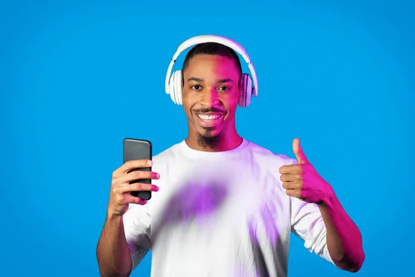 현대의 스마트폰 헤드폰을 사용하여 행복하게 잘생긴 아프리카 미국인 라이트에 엄지와 — 스톡 사진