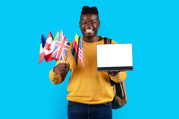 온라인에서 외국어를 Smiling Black Man Holding International Flags Laptop Computer — 스톡 사진