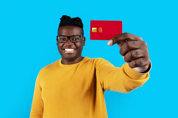 Uśmiechnięty Czarny Mężczyzna Okularach Wyświetlanie Czerwonej Karty Kredytowej Przed Kamerą — Zdjęcie stockowe