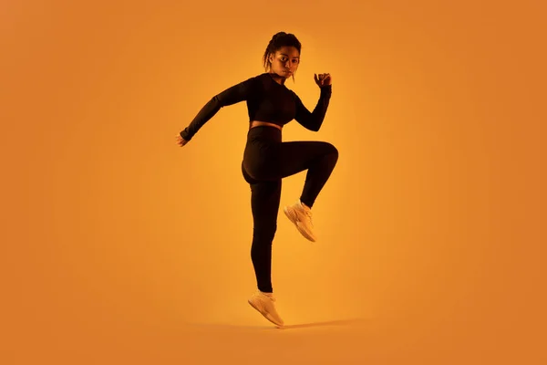 Sportliche Schwarze Frau Springt Und Macht Stretching Übungen Auf Orangefarbenem — Stockfoto