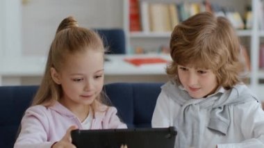 Çocuklar ve arkadaşlık. Şirin küçük bir çocuk ve kız internette dijital tablette sörf yapıyor, tatilde birlikte oynuyor, birbirleriyle konuşuyor, portreyi kapatıyorlar.