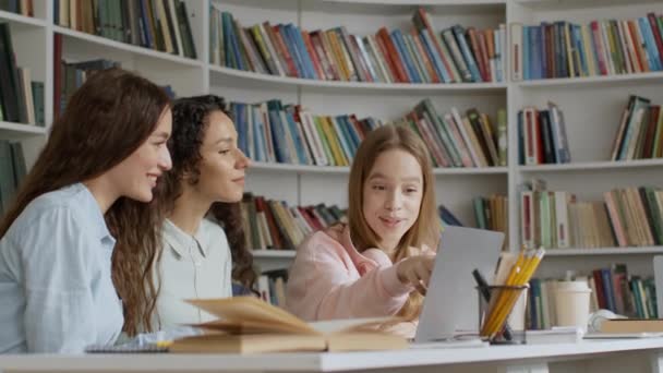 グループプロジェクト 3人の幸せな若い女性のグループは ノートパソコンで情報を読み取り ライブラリで一緒にエッセイを作成し ショットを追跡し スローモーション フリースペース — ストック動画