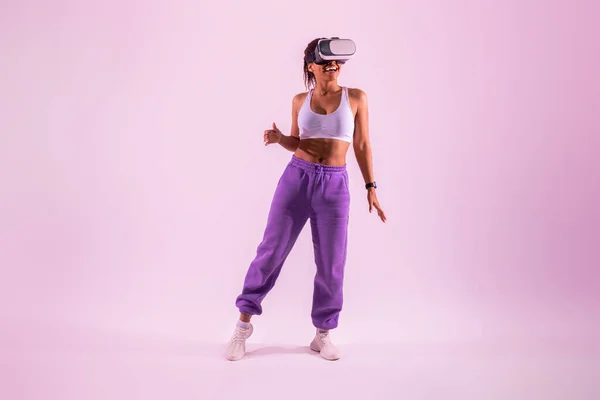 仮想現実ヘッドセットで踊る幸せな黒人女性は ピンクのネオンライトの背景に3D技術を探索しながら 彼女の仮想現実体験を楽しんで 完全な長さ — ストック写真