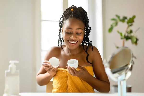 幸せな若いアフリカ系アメリカ人の女性は 家で顔クリームを使用してタオルに包まれ 美しい女性は 虚栄心のテーブルに座って 最新の有機的な美しさの製品をテストコピースペース — ストック写真