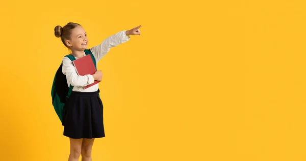 看那里 可爱的小女孩站在复印室旁边指指点点黄色背景的手指 微笑着展示自由的地方 做广告的东西 — 图库照片