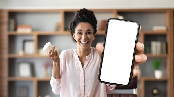 Beauty App. Happy Beautiful Woman Showing Big Blank Smartphone And Holding Cream Jar, Young Female Demonstrating Mobile Phone With White Screen For Application Design, Collage, Mockup