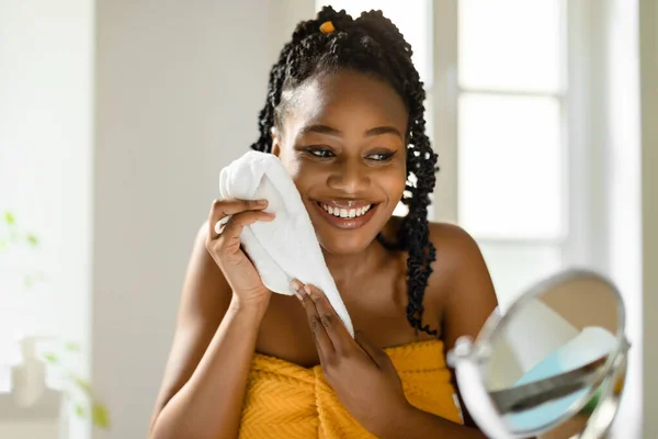 Χαρούμενη Μαύρη Γυναίκα Στεγνώνει Πρόσωπο Μαλακή Πετσέτα Κοιτάζοντας Μεγεθυντικό Καθρέφτη — Φωτογραφία Αρχείου