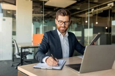 Şirketin CEO 'su ya da yöneticisi ofisinde evrak dolduruyor, dizüstü bilgisayarın önünde oturuyor, sözleşme imzalıyor ya da şirket mali raporlarını kontrol ediyor.