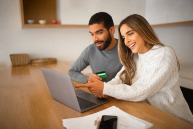 Gülümseyen bin yıllık Arap adam ve Avrupalı kadın dizüstü bilgisayar siparişi için ödeme yapıyorlar, kredi kartı kullanıyorlar, odada oturuyorlar. Alışverişkolikler online alışveriş ve satıştan, zımbırtıdan, vergi ödemelerinden ve muhasebeden keyif alıyorlar