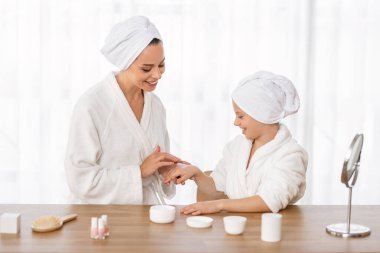 Cilt bakım konsepti. Anne ve kızı, evde güzel bir gün geçirirken nemlendirici krem sürerken, anne ve kız çocuğu için vücut losyonu sürerken,