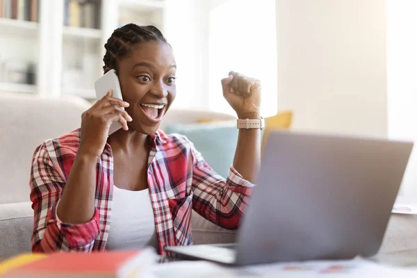 远程工作 自由职业概念 情绪激动的年轻黑人女士 她的辫子独立订约人在家工作 女人坐在地板上 用笔记本电脑和电话交谈 复制空间 — 图库照片