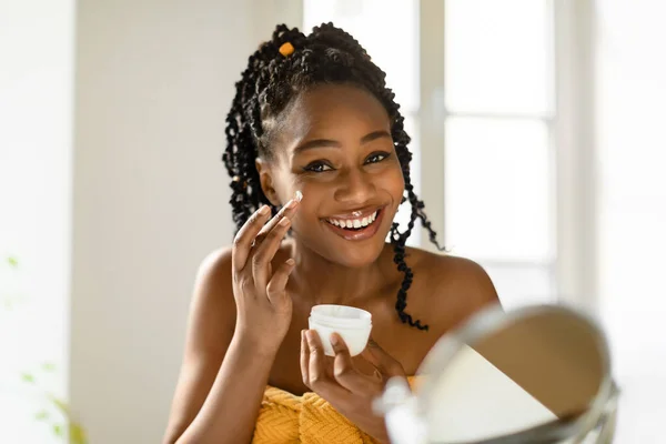 Retrato Hermosa Mujer Negra Aplicando Crema Facial Sonriente Señora Hidratante —  Fotos de Stock