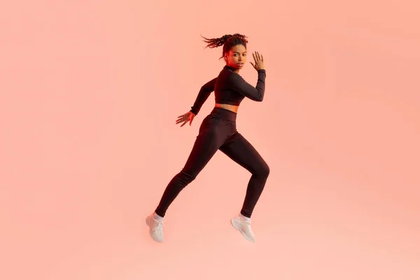 若いフィット黒の女性ジャンプ 桃のネオンの背景 完全な長さ コピースペースの上にフィッティングで心臓トレーニングを持っている フィットネスワークアウトのコンセプト — ストック写真