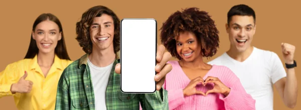 笑顔の異なる人々は 空白の画面でスマートフォンを表示します親指を構成します ベージュのスタジオの背景に隔離されたハートジェスチャー パノラマ 新しいウェブサイト アプリ オファーの推奨 — ストック写真