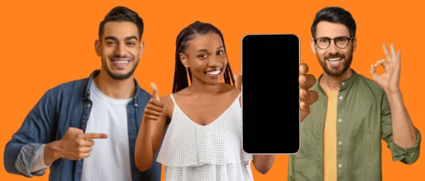 Happy millennial european, black and arab guys and woman pointing finger at smartphone with blank screen, make hand gesture ok and thumb up, approve website on orange background, studio panorama