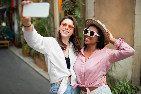 Uśmiechnięci Afrykańscy Kaukascy Turyści Kapeluszu Okularach Przeciwsłonecznych Robiący Selfie Smartfonie — Zdjęcie stockowe