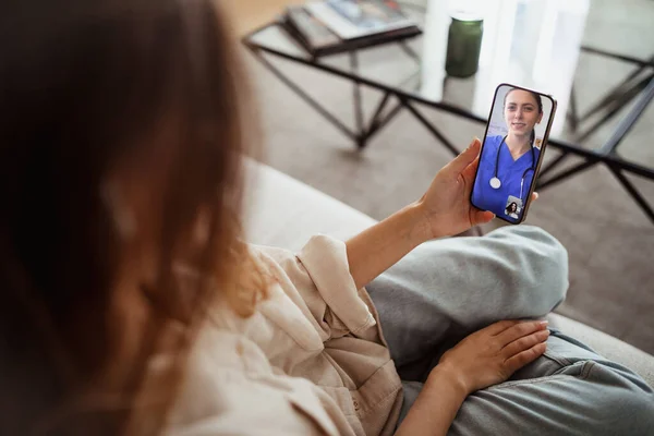 stock image Young asian woman has video call with doctor in room interior, cropped. Healthcare app, treatment disease remotely, medicine at home, new normal with gadget during covid-19 quarantine