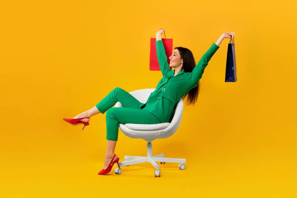 Mutlu Alışverişkolik Kadın Sandalyede Oturuyor Sarı Stüdyo Arka Planında Izole — Stok fotoğraf
