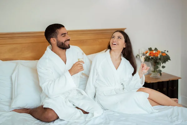 Щаслива Пара Ігристе Вино Розслабляючись Сидячи Ліжку Готельному Номері Одягненому — стокове фото