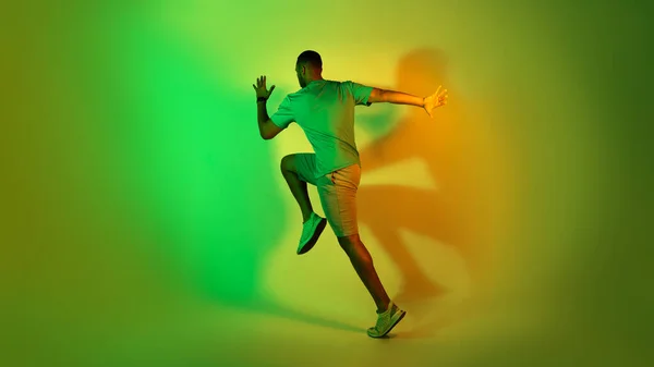 Афроамериканец Бегущий Зеленой Неоновой Студии Полнометражный Снимок Неузнаваемого Спортсмена Носящего — стоковое фото