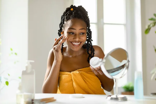 Šťastná Krásná Černoška Dívá Zrcadla Aplikuje Hydratační Pleťový Krém Takže — Stock fotografie