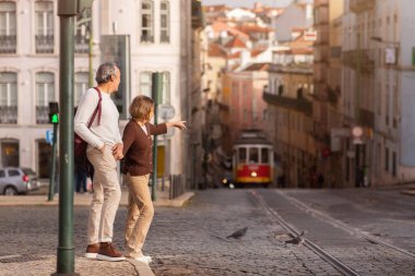Lizbon 'da yürüyen kıdemli turistler, dışarıda Tram' ı işaret eden ve Portekiz 'de caddeden karşıya geçen kadınlar. Tatil Turu ve Ulaşım Konsepti.