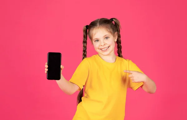 Sorrindo Pequena Menina Apontando Branco Smartphone Com Tela Preta Sua — Fotografia de Stock