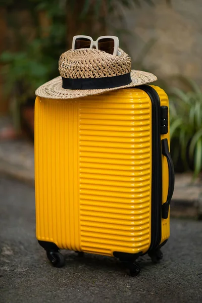 通りに帽子とサングラス付きの黄色のスーツケース 観光客の垂直方向の旅行のためのアクセサリー 閉じると 旅行休暇の準備 夏休みとアクティブなライフスタイル — ストック写真