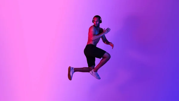 Атлетический Афроамериканец Прыгает Позируя Воздухе Слушая Музыку Носящую Беспроводные Наушники — стоковое фото