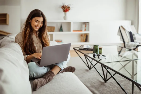 stock image Smiling busy pretty young asian female typing on laptop in living room interior. Meeting remotely, work, business, freelance at home, new normal with technology and social networks