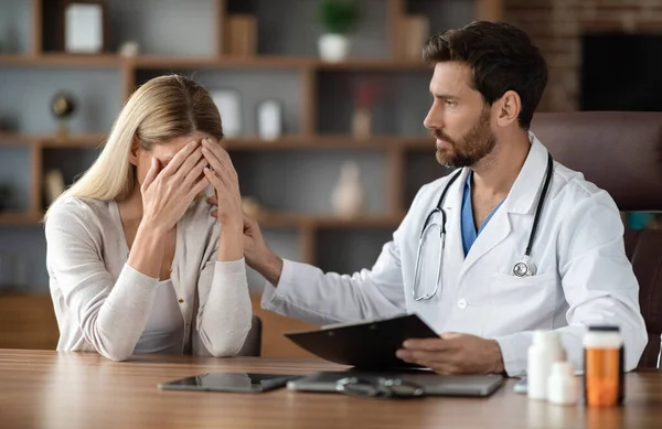 Male Therapist Comforting Crying Young Woman After Sharing Bad Diagnosis At Meeting In Clinic, Physician Man Soothing Depressed Lady, Stroking Her Shoulder And Looking With Empathy, Closeup