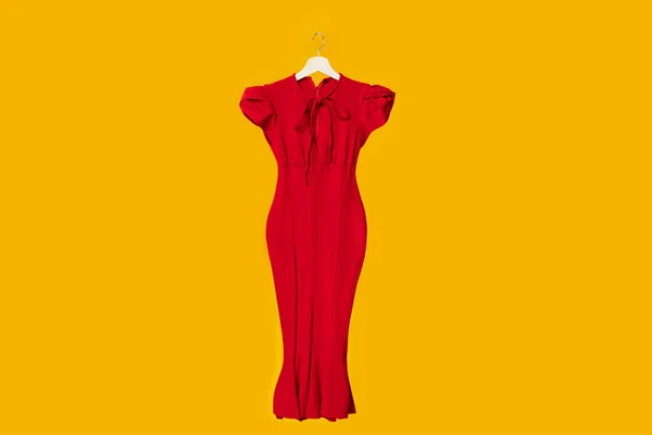 典雅的红色连衣裙挂在木制衣架上 隔离在黄色工作室背景特写镜头中 免费复制空间 — 图库照片