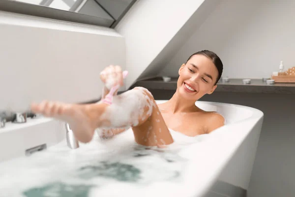 自宅のバスルームで新しい安全カミソリ入浴を使用して髪を削除し 滑らかな足を持つ陽気な女性 ボディケアと分解ルーチンの概念 選択的フォーカス — ストック写真